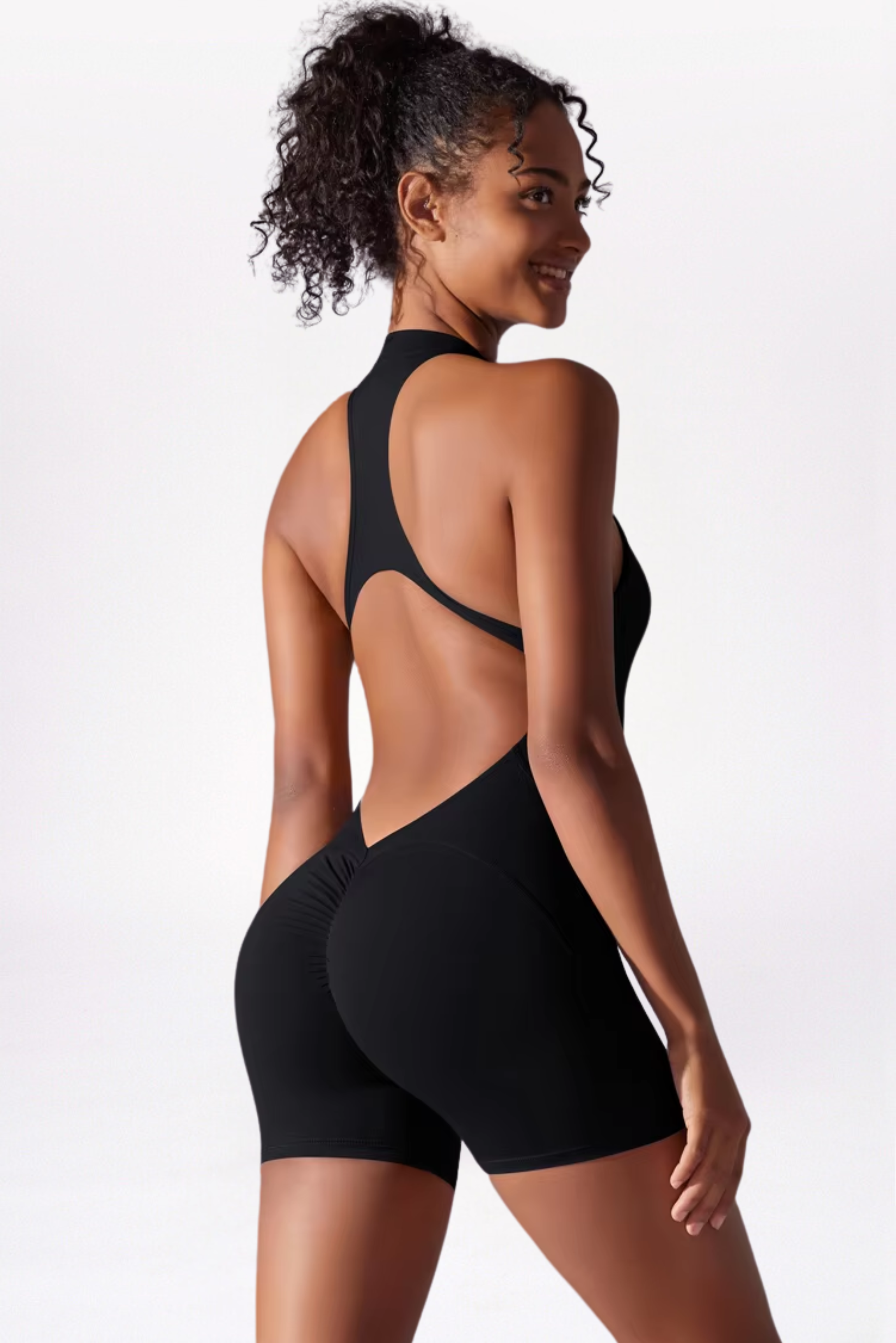 Woman wearing a black bodysuit with open back on a white background