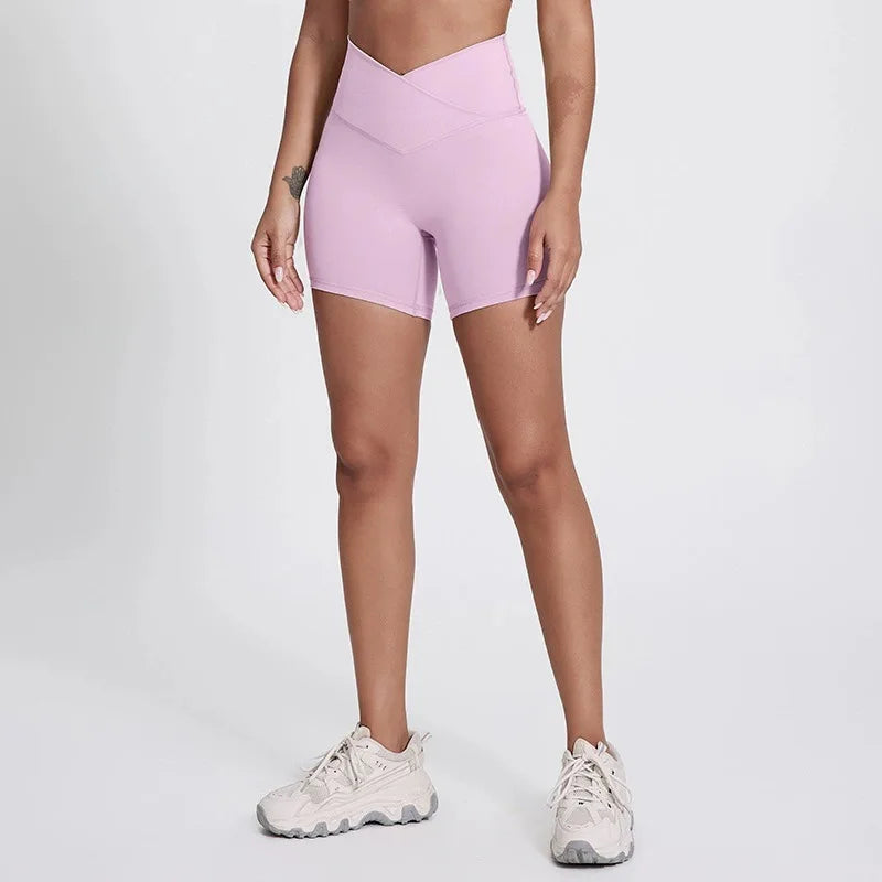 Person wearing light pink high-waisted shorts on a plain background brand Gymelle