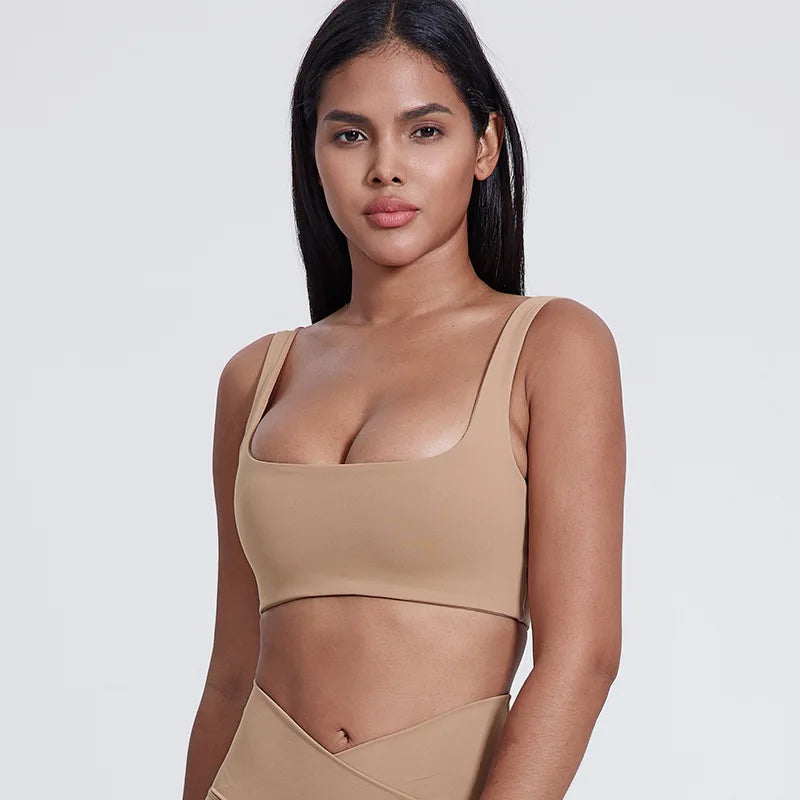 Woman wearing a beige sports bra and leggings on a white background brand Gymelle