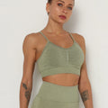 Woman wearing a green sports bra and leggings set against a white background